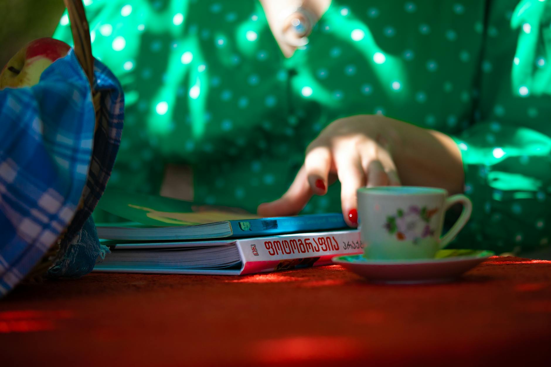 A serene setting with a hand on a book and a cup of tea. Sunlit and relaxing.