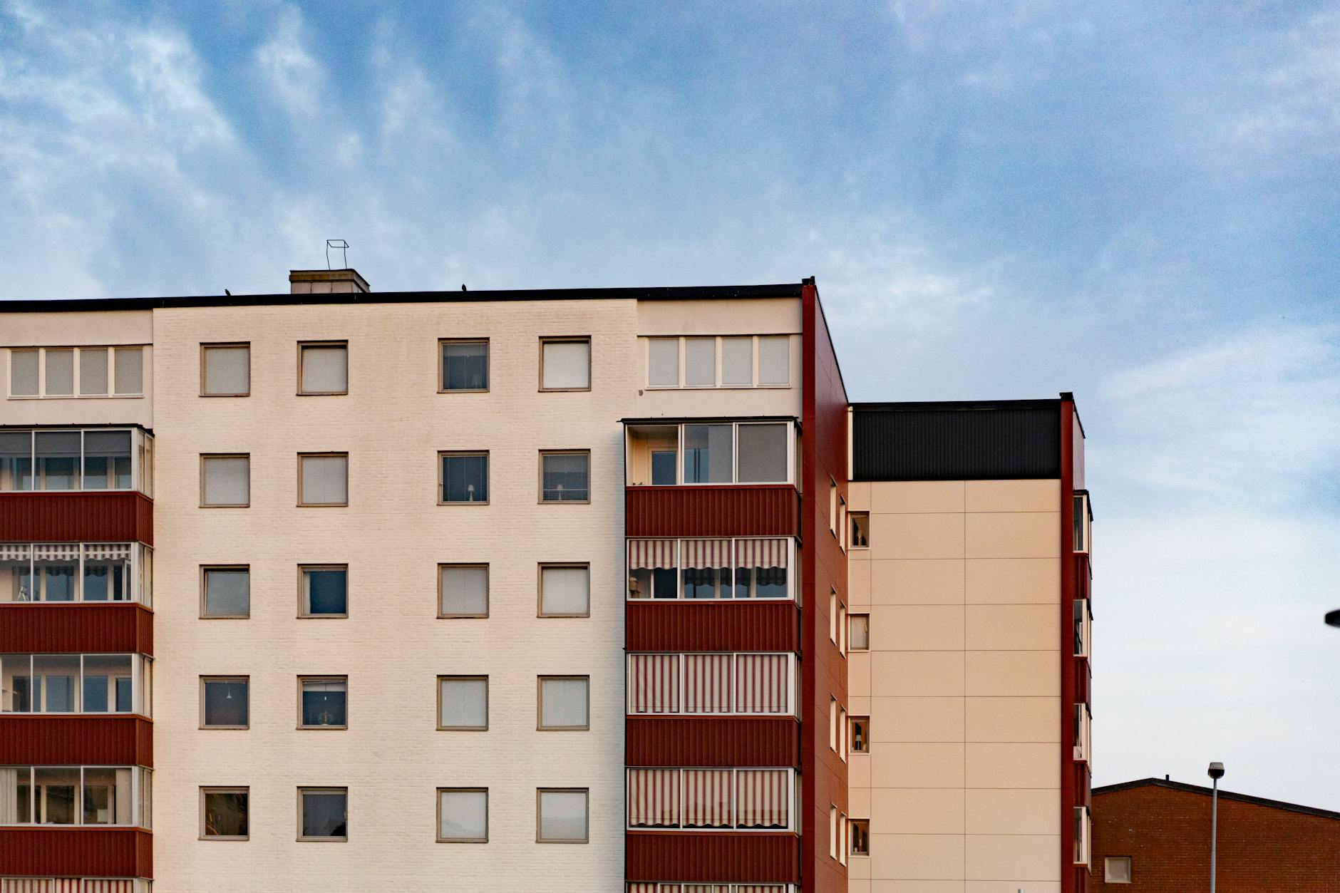 Contemporary apartment building facade with multiple windows and balconies against a clear sky.
