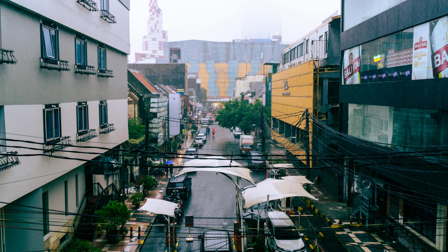 A rainy day in a Jakarta urban street showcasing modern and traditional architecture.