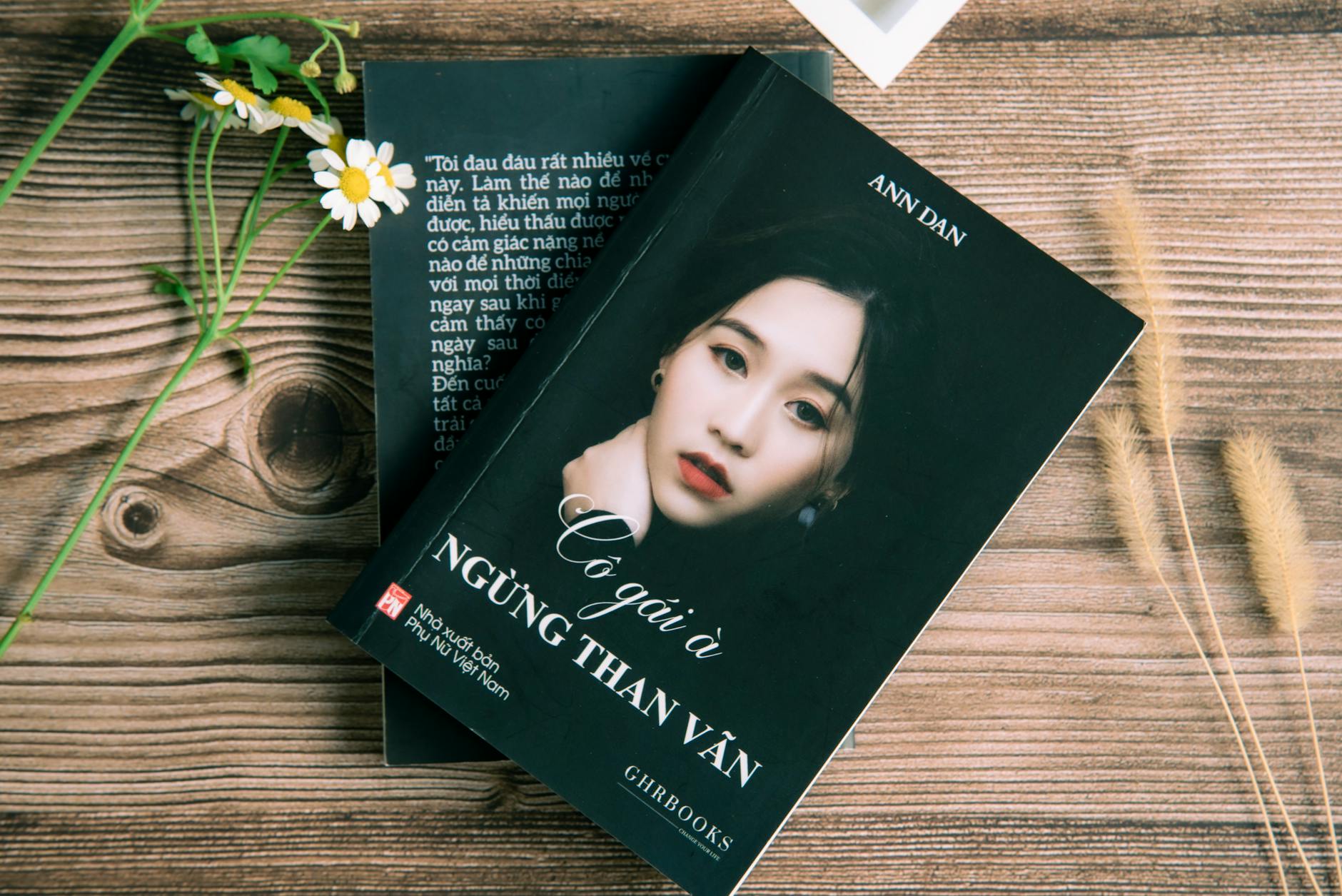 Vietnamese book cover shot in a flat lay showing elegant modern design on wooden backdrop.