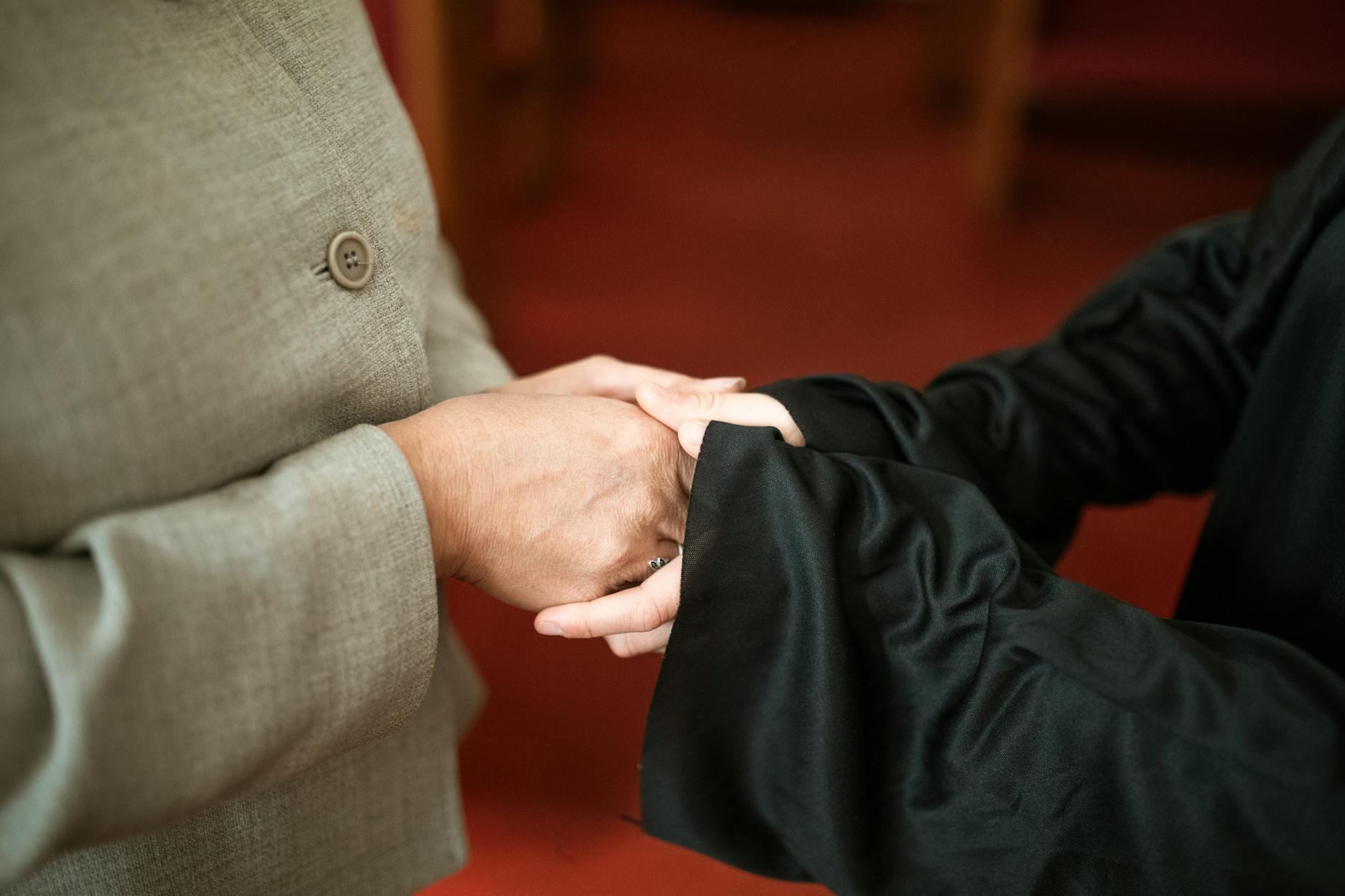 Two people expressing connection and support through hand holding.